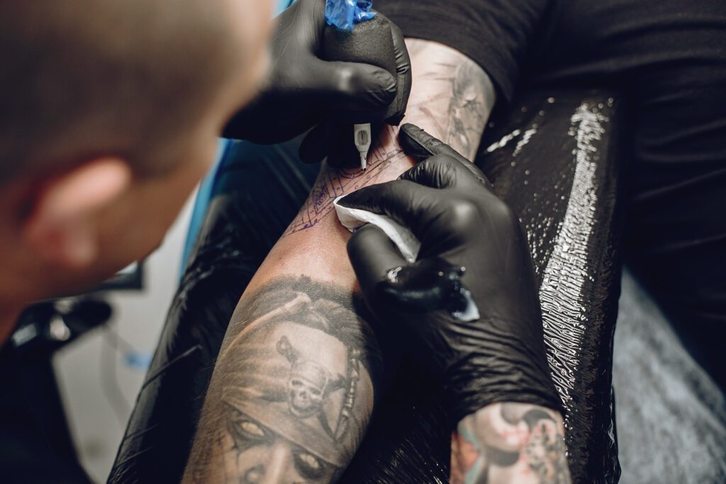 um mestre certificado com um curso profissional de tatuagem trabalha no braço de um cliente
